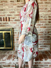 Person wearing a floral kimono in front of a brick wall.