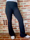Person wearing black flare yoga pants standing against a brick wall.