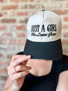 Person wearing a cap with 'Just a Girl Who Loves Jesus' text against a brick wall.