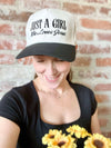 Person wearing a cap with 'Just a Girl Who Loves Jesus' text against a brick wall.